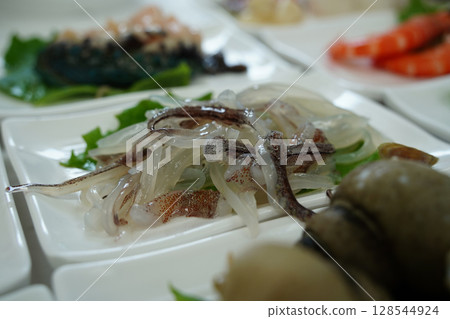 Close-up of Freshly Sliced Raw Squid Served as Side Dish in Korean Seafood Restaurant 128544924