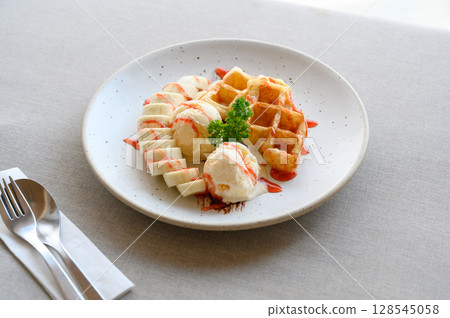 tasty dessert. Croffle serve with ice cream, banana and topping with strawberry syrup. tasty dessert. Croffle serve with ice cream, banana and topping with strawberry syrup. 128545058