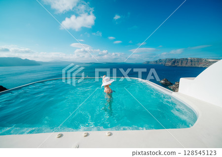 Woman swimming in a pool on the Greek island of Santorini 128545123