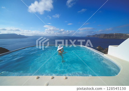 一名女子在希臘聖托里尼島的游泳池裡游泳 128545130