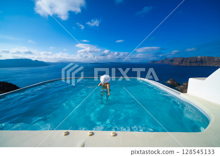 一名女子在希臘聖托里尼島的游泳池裡游泳 128545133