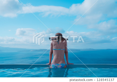 一名女子在希臘聖托里尼島的游泳池裡游泳 128545137