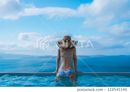 Woman swimming in a pool on the Greek island of Santorini 128545140