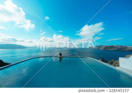 Woman swimming in a pool on the Greek island of Santorini 128545157