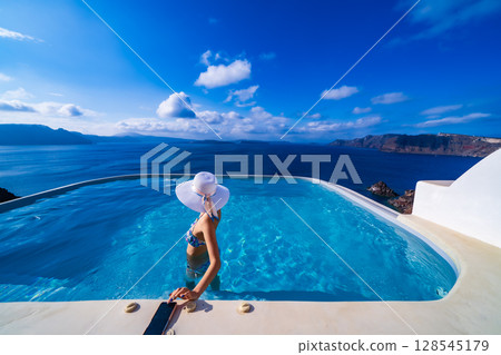 Woman swimming in a pool on the Greek island of Santorini 128545179