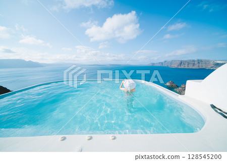 Woman swimming in a pool on the Greek island of Santorini 128545200