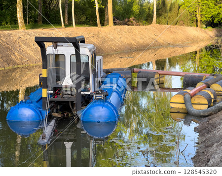 A specialized cleaning machine works in a shallow waterway, removing debris and maintaining the environment in a vibrant city park A specialized cleaning machine works in a shallow waterway, removing debris and maintaining the environment in a vibrant city park 128545320