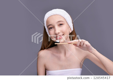 Caucasian female teen with headband holding bamboo toothbrush smiling Caucasian female teen with headband holding bamboo toothbrush smiling 128545417