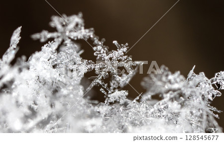 Macro snowflakes showing intricate winter details on dark background Macro snowflakes showing intricate winter details on dark background 128545677