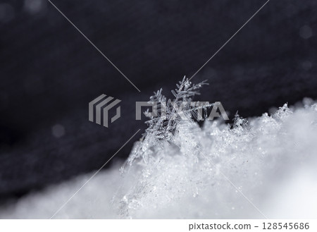 Macro snowflakes showing intricate winter details on dark background Macro snowflakes showing intricate winter details on dark background 128545686