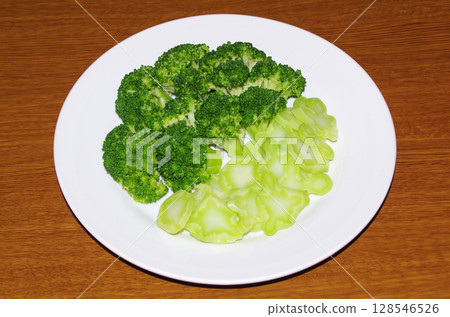 Fresh, beautiful green broccoli cut into bite-sized pieces and boiled, served on a plate (wood grain background) 128546526