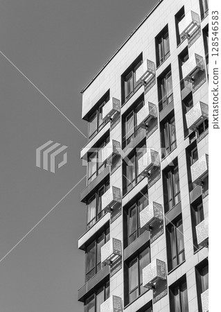 Skyscraper on sky background, monochrome. High rise building with copy space. Modern architecture, black and white. Business office building. Geometric lines in architecture. Modern scraper exterior. Skyscraper on sky background, monochrome. High rise building with copy space. Modern architecture, black and white. Business office building. Geometric lines in architecture. Modern scraper exterior. 128546583