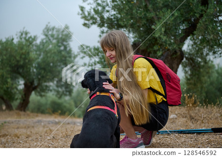 Young Woman Enjoying a Nature Hike with Her Dog and Backpack Young Woman Enjoying a Nature Hike with Her Dog and Backpack 128546592