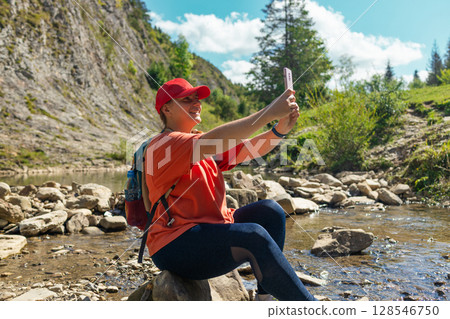 Young Female Hiker Taking a Selfie While Resting by a Mountain Stream Young Female Hiker Taking a Selfie While Resting by a Mountain Stream 128546750