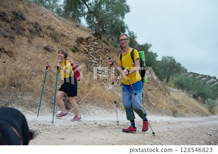 Happy Couple Hiking in Scenic Mountain Trail with Trekking Poles Happy Couple Hiking in Scenic Mountain Trail with Trekking Poles 128546823