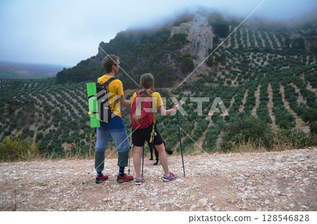Couple Hiking in Scenic Mountain Landscape with Trekking Poles 128546828