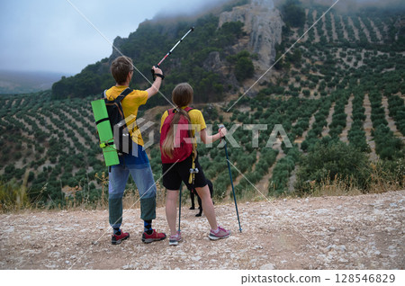 Active Couple Hiking with Dog Through Mountainous Olive Groves 128546829