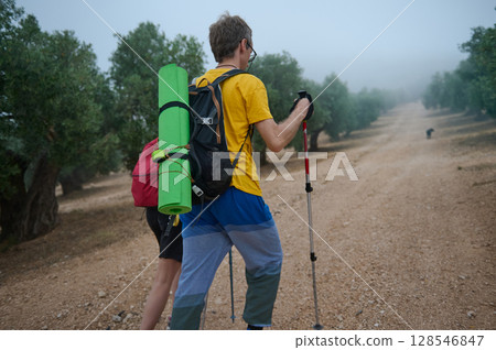 Hikers Trekking Through a Scenic Forest Pathway with Outdoor Gear Hikers Trekking Through a Scenic Forest Pathway with Outdoor Gear 128546847