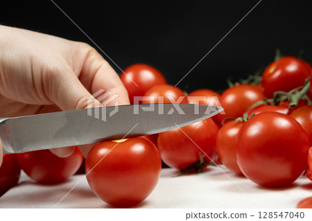 Cutting Mini Ripe Tomatoes on Cutting Board. Healthy Food Preparation. Cutting Mini Ripe Tomatoes on Cutting Board. Healthy Food Preparation. 128547040