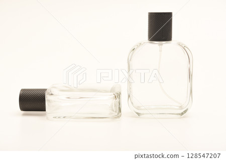 Empty glass perfume bottle. Elegant transparent flacon once filled with fragrance, now standing clean and minimalistic, ideal for cosmetics or beauty-related concepts. Empty glass perfume bottle. Elegant transparent flacon once filled with fragrance, now standing clean and minimalistic, ideal for cosmetics or beauty-related concepts. 128547207