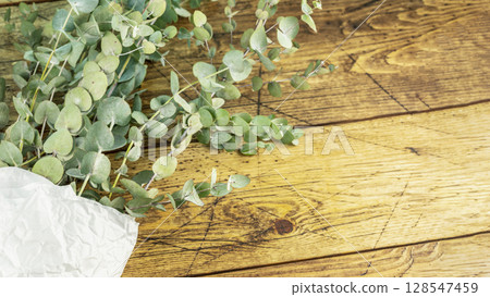 Bouquet with eucalyptus branches on wooden background. Eco friendly holiday composition with eucalypt bouquet. Wellness in the bath. Floristic background. Flat lay, copy space Bouquet with eucalyptus branches on wooden background. Eco friendly holiday composition with eucalypt bouquet. Wellness in the bath. Floristic background. Flat lay, copy space 128547459