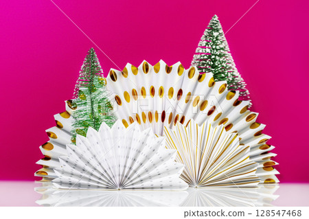 White table with paper fans and new year trees on magenta background with space for product presentation. Christmas and New Year holiday background for display of advertising products 128547468