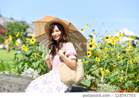 Asian woman holding a parasol in front of a sunflower field 128547703