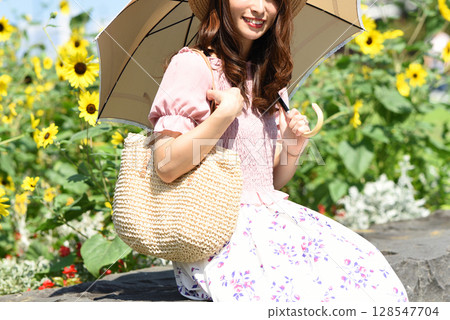 Asian woman holding a parasol in front of a sunflower field 128547704