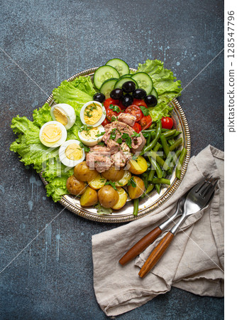 Nicoise salad with tuna, olives, green beans, tomatoes and quail eggs on a bed of lettuce 128547796