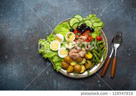 Nicoise salad with tuna, olives, green beans, tomatoes and quail eggs on a bed of lettuce with copy space 128547819