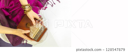 Woman holding kalimba in her hands and playing. Relaxing at home, Me time, self care and sound meditation banner. Woman enjoy melodious sound of thumb piano playing. Closeup, banner size, copy space Woman holding kalimba in her hands and playing. Relaxing at home, Me time, self care and sound meditation banner. Woman enjoy melodious sound of thumb piano playing. Closeup, banner size, copy space 128547879