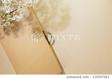 Eco friendly shopping and delivery service concept. Sustainable life style with cardboard box on cardboard background with white flowers and shadows. Plastic free and eco packaging. Mockup, copy space 128547881