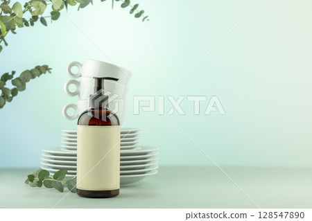 Mockup of natural dish detergent. Concept of eco friendly cleaning dishes. Bottle with dish detergent with clean plates and cups on blue background with eucalyptus branches. Front view, copy space 128547890