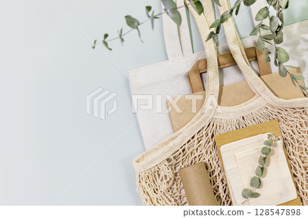 Eco friendly shopping, delivery service. Sustainable still life with textile bags, paper bag, mesh bag, wrapping paper on blue background. Zero Waste, plastic free, eco packaging concept. Copy space 128547898