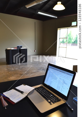 A laptop is open on a desk with a notebook and a pen A laptop is open on a desk with a notebook and a pen 128548186