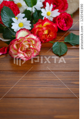 Romantic roses and daisies on wooden table surface Romantic roses and daisies on wooden table surface 128548390