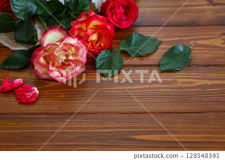 Red and pink garden flowers resting on timber Red and pink garden flowers resting on timber 128548391