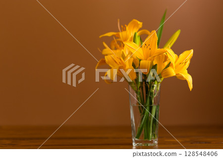 Fresh bouquet of orange lilies on a brown background Fresh bouquet of orange lilies on a brown background 128548406