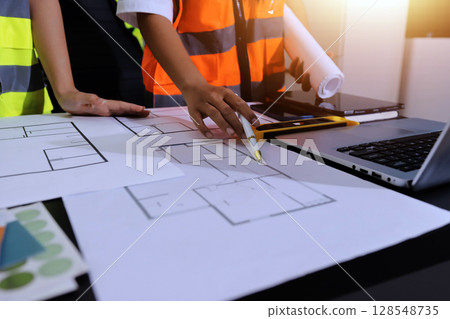 Closeup of team of industrial engineers meeting analyze machinery blueprints consult project on table in manufacturing factory. Working in manufacturing plant or production plant. 128548735