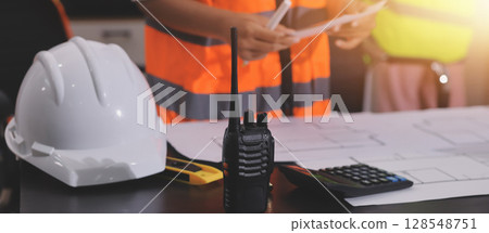 Closeup of team of industrial engineers meeting analyze machinery blueprints consult project on table in manufacturing factory. Working in manufacturing plant or production plant. 128548751