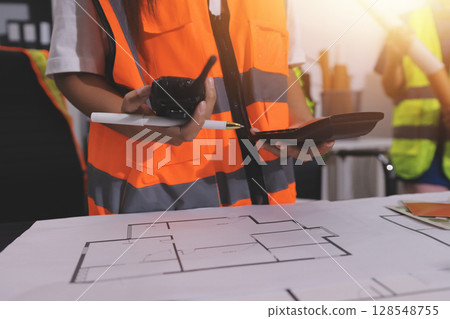 Closeup of team of industrial engineers meeting analyze machinery blueprints consult project on table in manufacturing factory. Working in manufacturing plant or production plant. 128548755