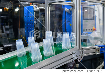 Plastic cup on conveyor belt in distribution warehouse.parcels transportation system concept. Plastic cup on conveyor belt in distribution warehouse.parcels transportation system concept. 128548915