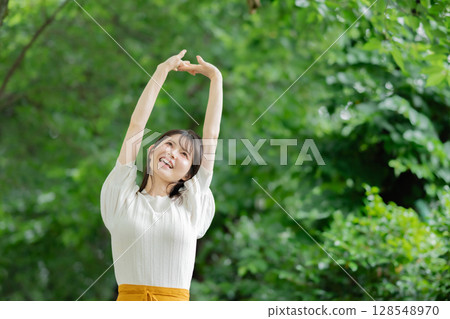 A woman stretching in the fresh greenery A woman stretching in the fresh greenery 128548970