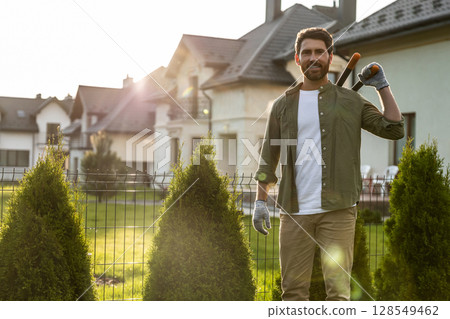 Confident young bearded man wording in the garden and looking resolute Confident young bearded man wording in the garden and looking resolute 128549462