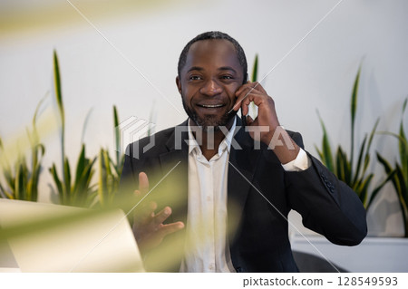 Businessman having a phone call and smiling positively Businessman having a phone call and smiling positively 128549593