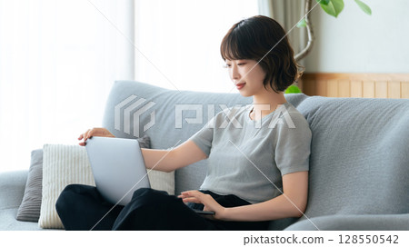 坐長沙發和使用計算機的婦女 128550542