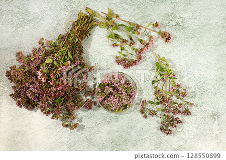 Bouquet of oregano and petals in a glass cup on a concrete table for collecting useful herbs and treatment according to folk recipes, Medicinal herbal tea, concept of alternative folk medicine, Bouquet of oregano and petals in a glass cup on a concrete table for collecting useful herbs and treatment according to folk recipes, Medicinal herbal tea, concept of alternative folk medicine, 128550899