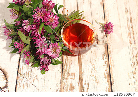 Clover infusion in a glass with a bouquet of flowers, Medicinal herbal tea, the concept of alternative folk medicine, advertising a green pharmacy, a collection of useful herbs for treatment according 128550907