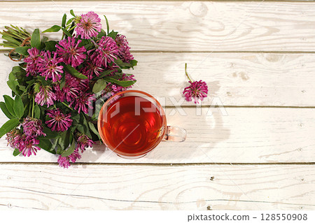 Clover infusion in a glass with a bouquet of flowers, Medicinal herbal tea, the concept of alternative folk medicine, advertising a green pharmacy, a collection of useful herbs for treatment according 128550908