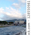 Scenic urban landscape along Terek River: Vladikavkaz City Hall standing proudly on the embankment, Caucasus mountains in background 128550981